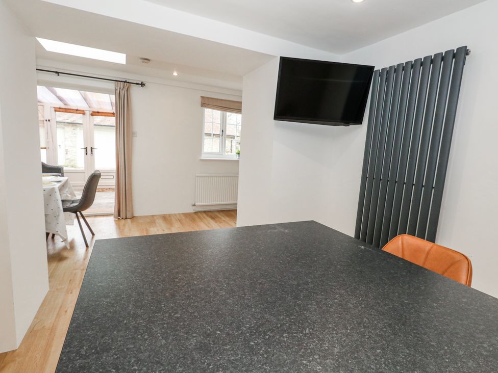 A dining room with a table and television at Long Barn in Burton Bradstock