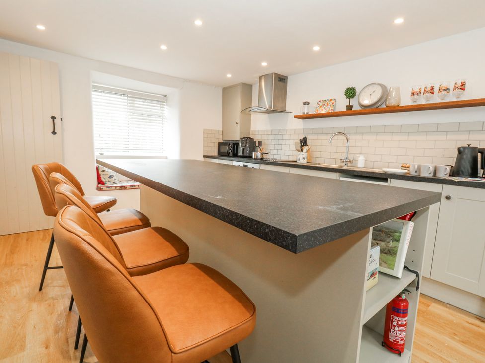 A kitchen with a bar island and appliances at Long Barn in Burton Bradstock