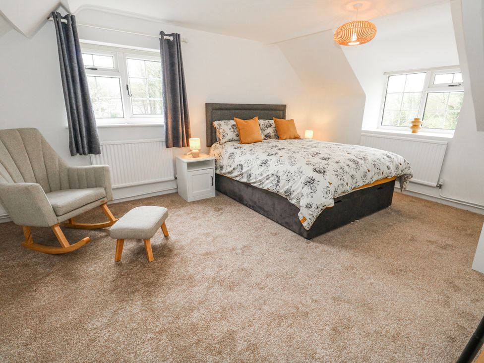 A bedroom with a bed and rocking chair at Long Barn in Burton Bradstock