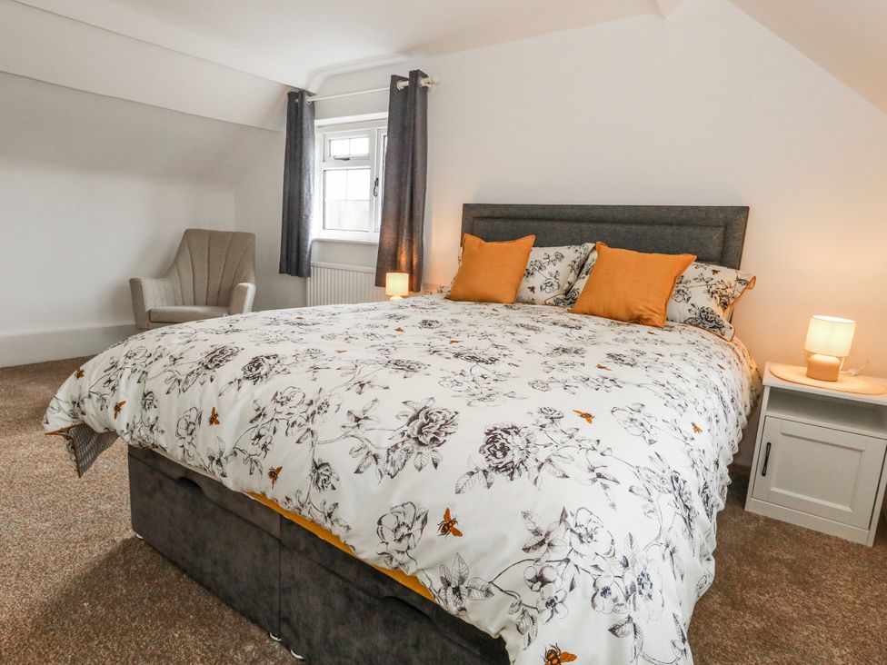 A bedroom with a bed and armchair at Long Barn in Burton Bradstock