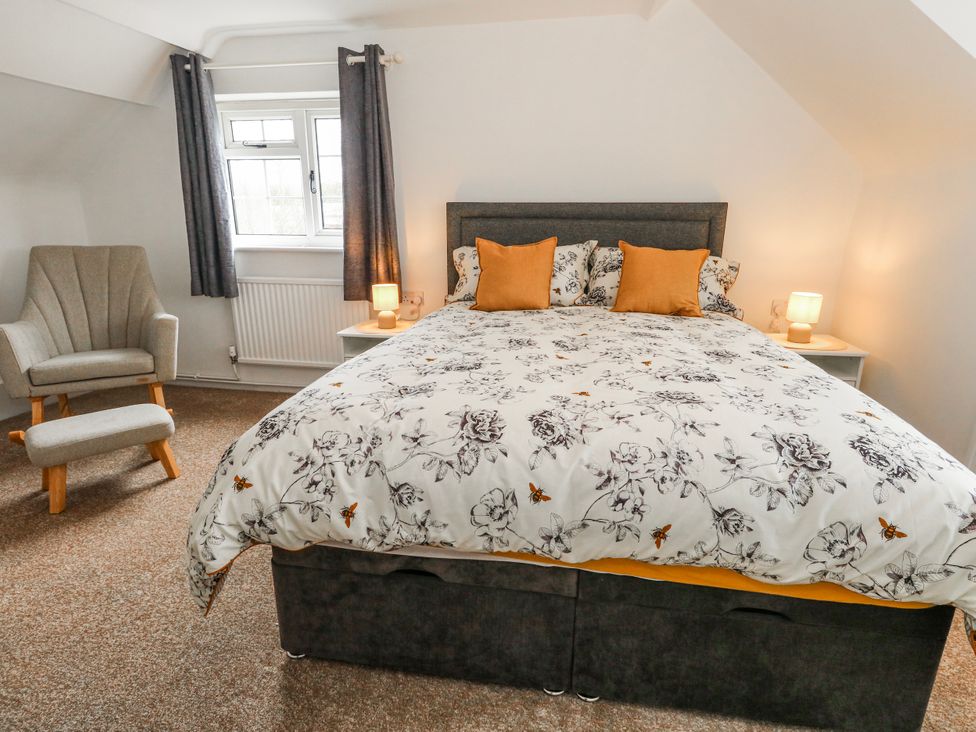 A bedroom with a double bed and armchair at Long Barn in Burton Bradstock
