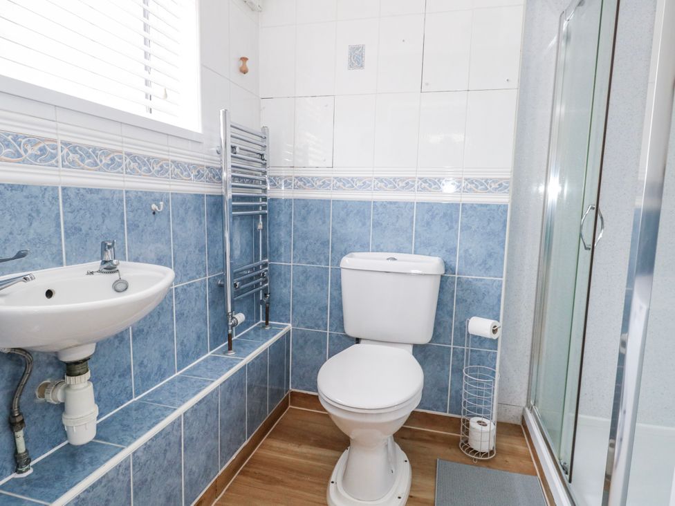 A bathroom with a sink, toilet, and shower at Long Barn in Burton Bradstock