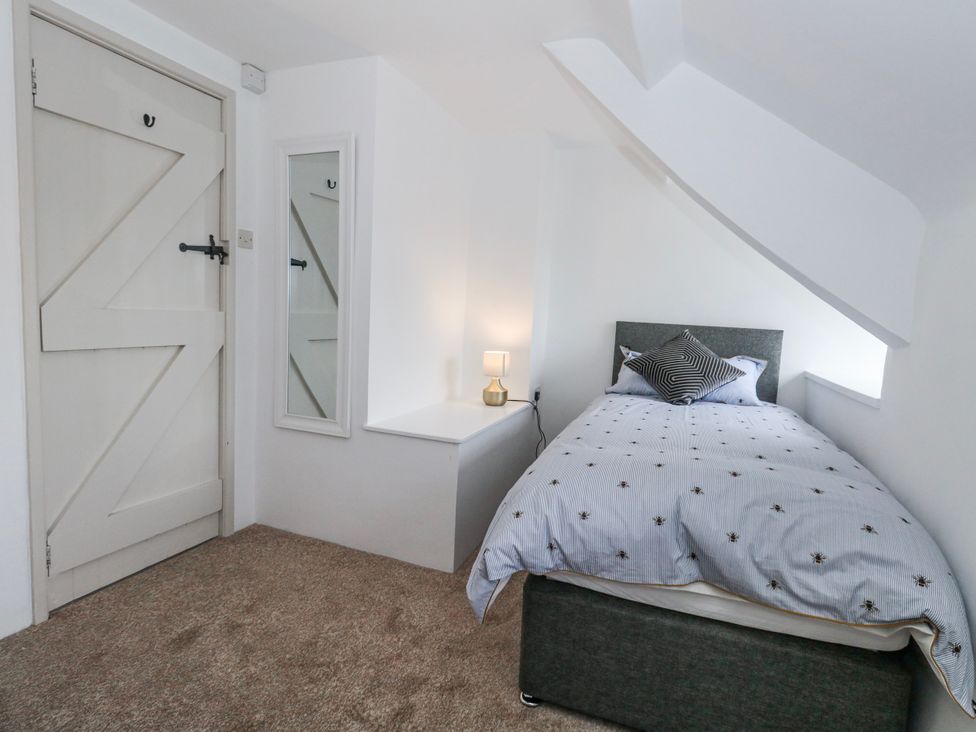 A bedroom with a bed and mirror at Long Barn in Burton Bradstock