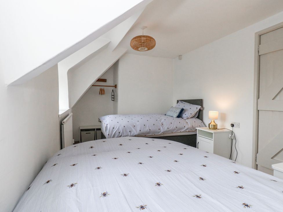 A bedroom with two beds and a lamp at Long Barn in Burton Bradstock