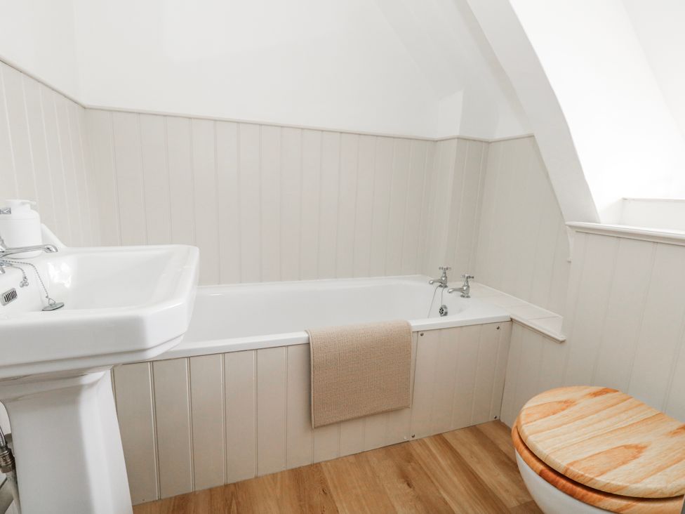 A bathroom with a bathtub, sink, and toilet at Long Barn in Burton Bradstock