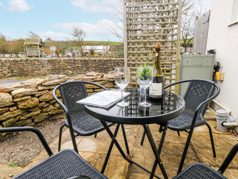 A table with glasses and a wine bottle in an outdoor area at Long Barn in Burton Bradstock