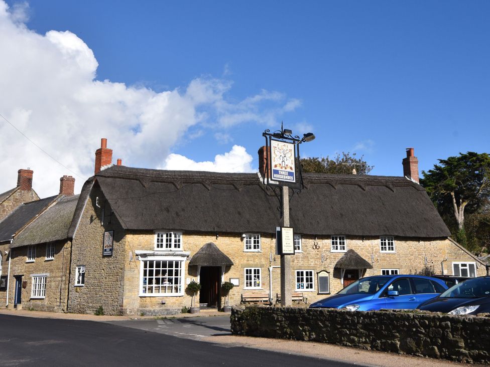 A building with a thatched roof at Three Horseshoes in Burton Bradstock