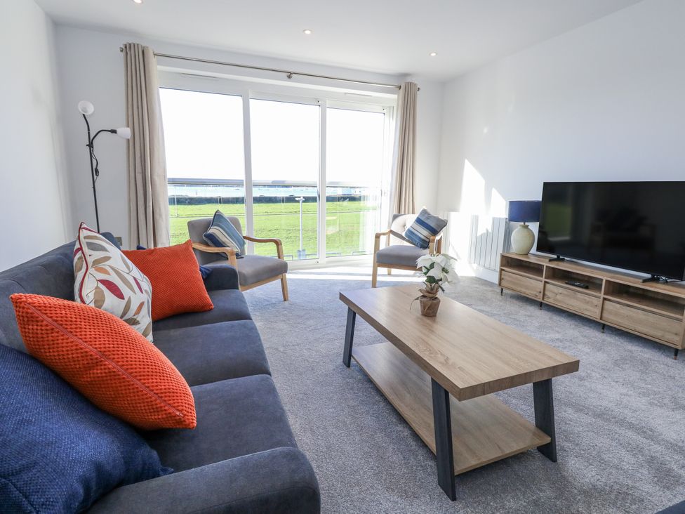A living room with a sofa, armchair, coffee table and television at Seafern House 36B Poole