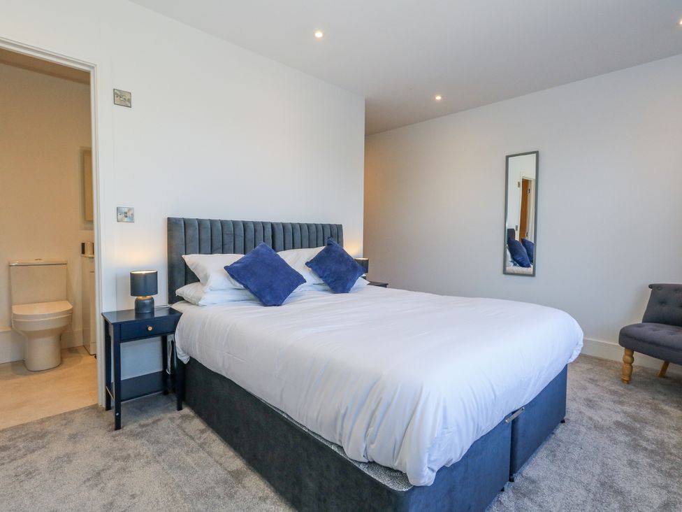 A bedroom with a bed, bedside table, and a bathroom doorway at Seafern House 36B, Poole