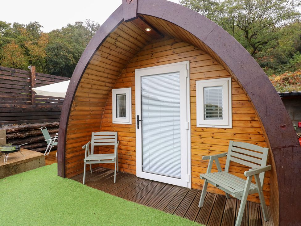 An outdoor area with wooden pod structure and seating at Cwtch Bach Aberdare