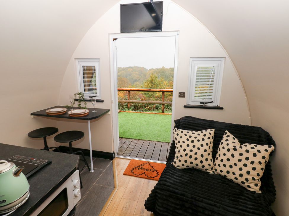An interior view with table, sofa and kitchen area at Cwtch Bach in Aberdare