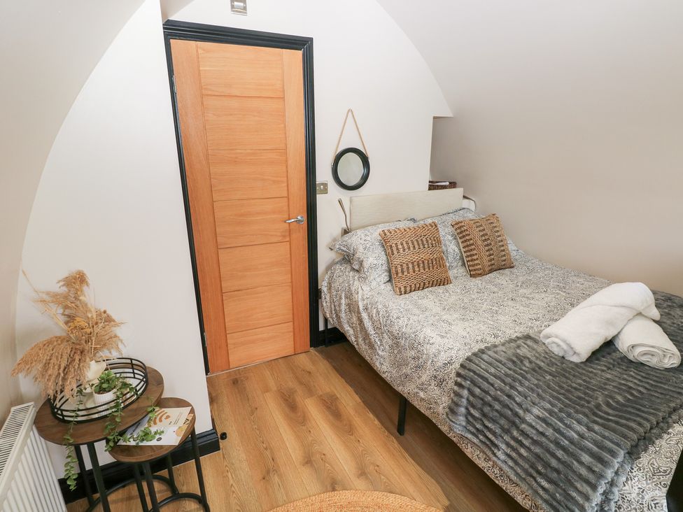 A bedroom with a bed, table, and door at Cwtch Bach in Aberdare