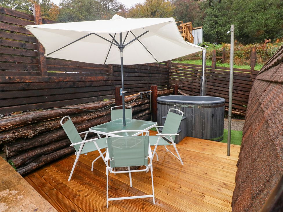 An outdoor area with a table, chairs, and a hot tub at Cwtch Bach in Aberdare