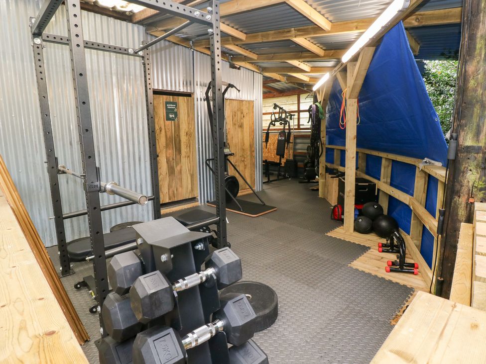 A gym with a squat rack and dumbbells at Cwtch Bach Aberdare