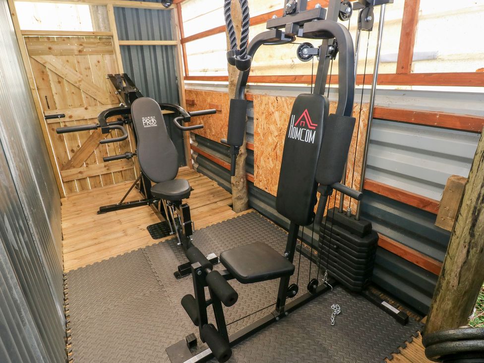 Exercise equipment including a weight machine and a bench at Cwtch Bach Aberdare