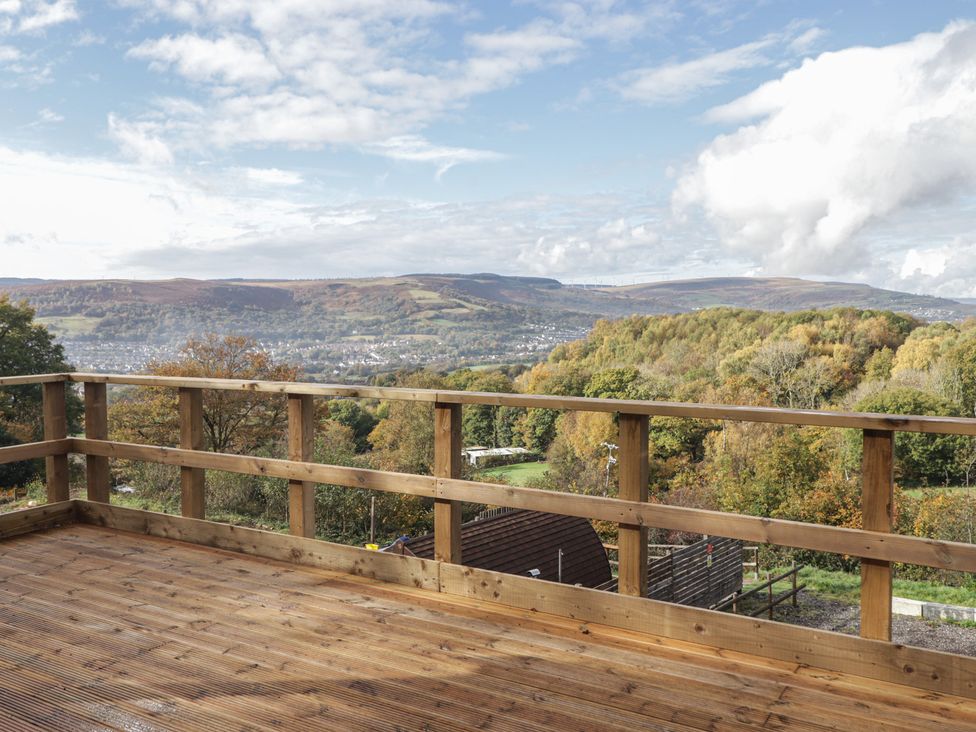A balcony with a wooden railing and view of hills at Cwtch Bach in Aberdare