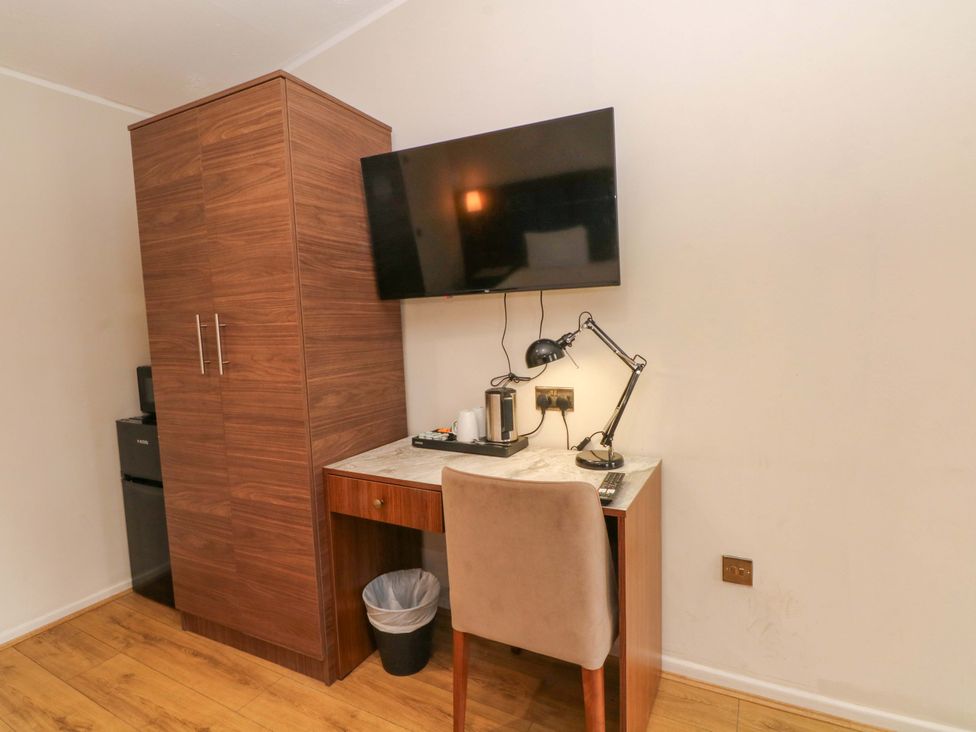 An office with a desk, lamp, television, and cabinet at 1 bed no. 1