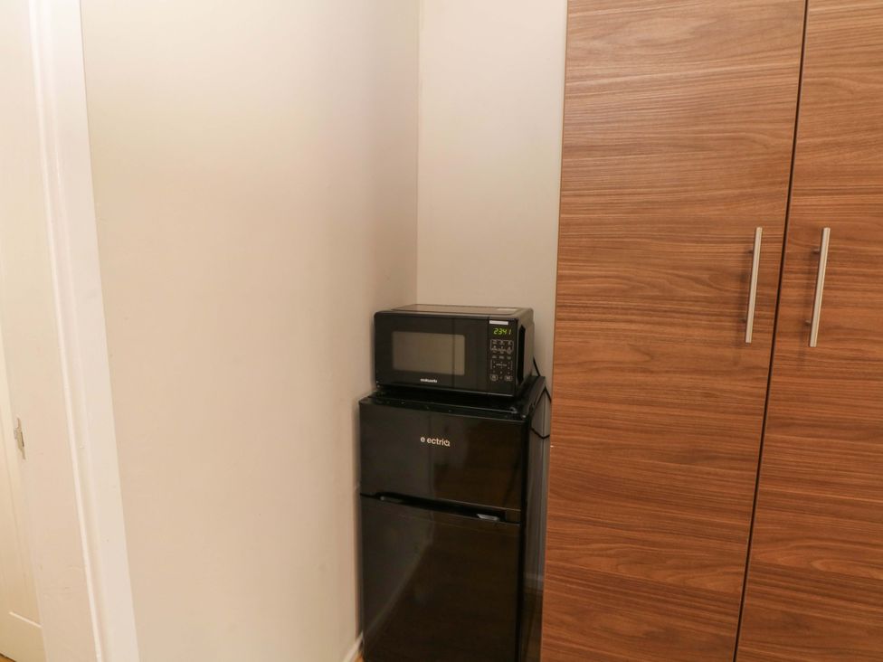 A microwave on top of a refrigerator in a kitchen at 1 bed no. 1
