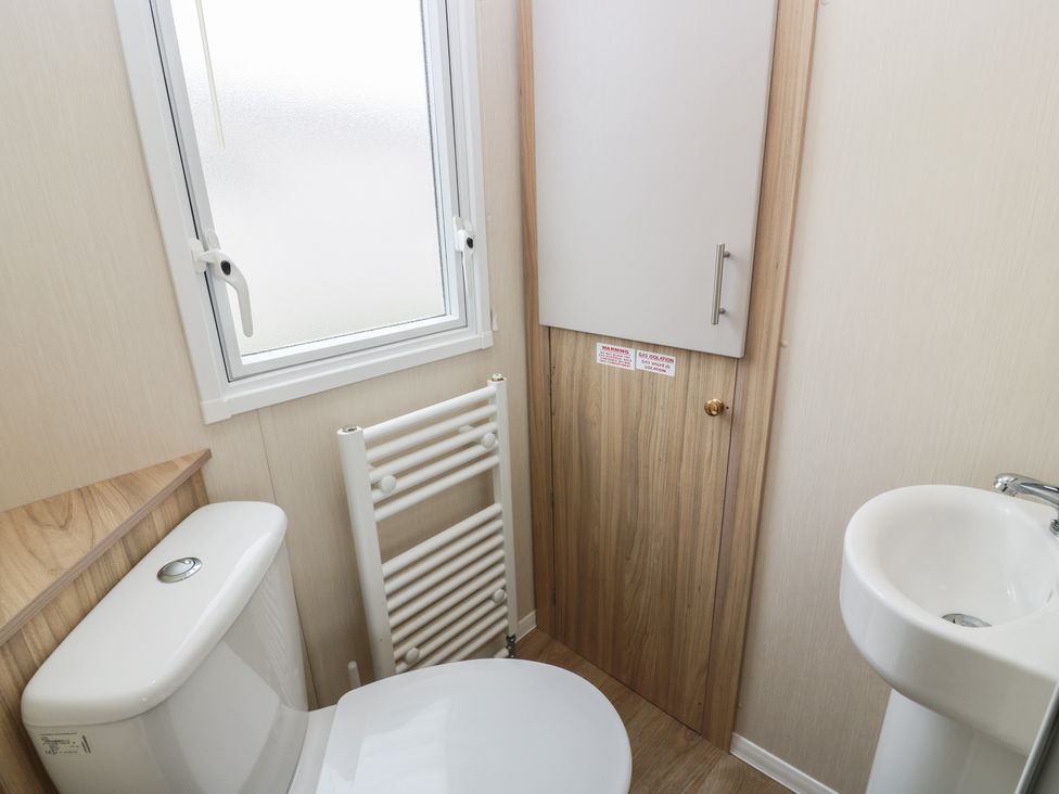 A bathroom with a toilet, sink, and radiator at Peaceful in Stranraer