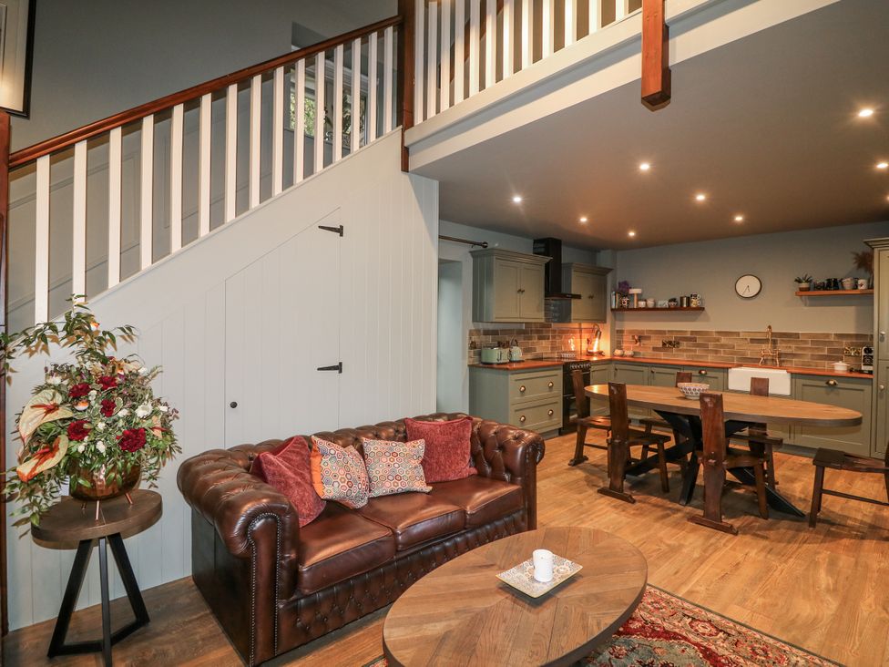 A living room with a sofa and a kitchen area at Robins Rest at The Lodge Kilmacthomas