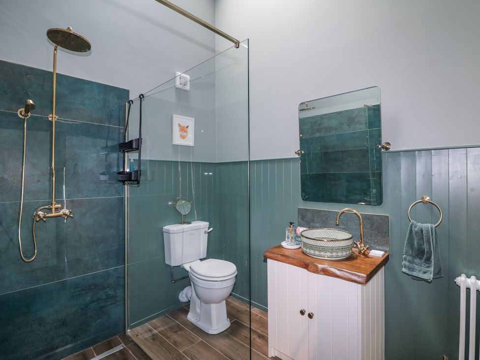 A bathroom with a shower, toilet, sink and mirror at Robins Rest at The Lodge Kilmacthomas