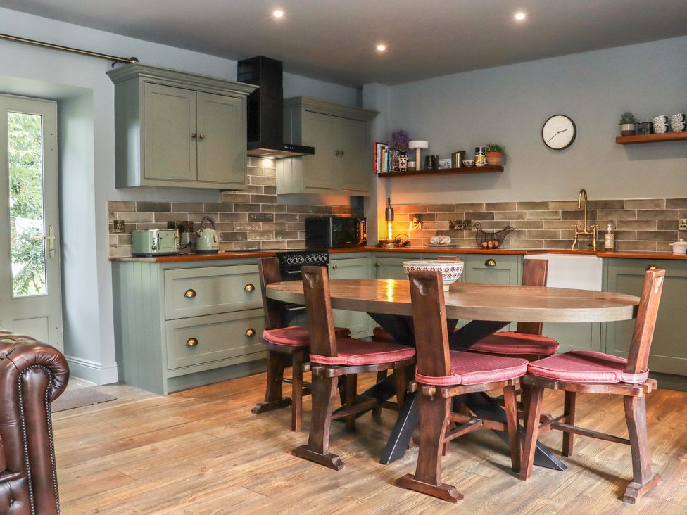 A kitchen with cabinets and a round dining table at Robins Rest at The Lodge in Ahanaglogh near Kilmacthomas, County Waterford