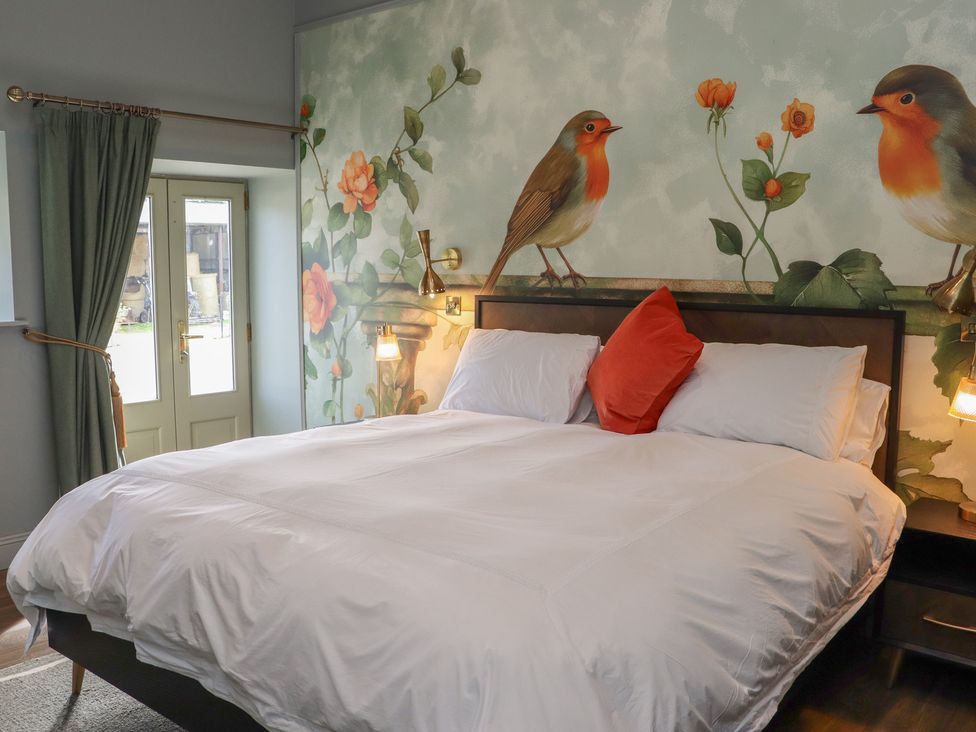 A bedroom with a bed and a wall mural of birds at Robins Rest at The Lodge Ahanaglogh near Kilmacthomas, County Waterford