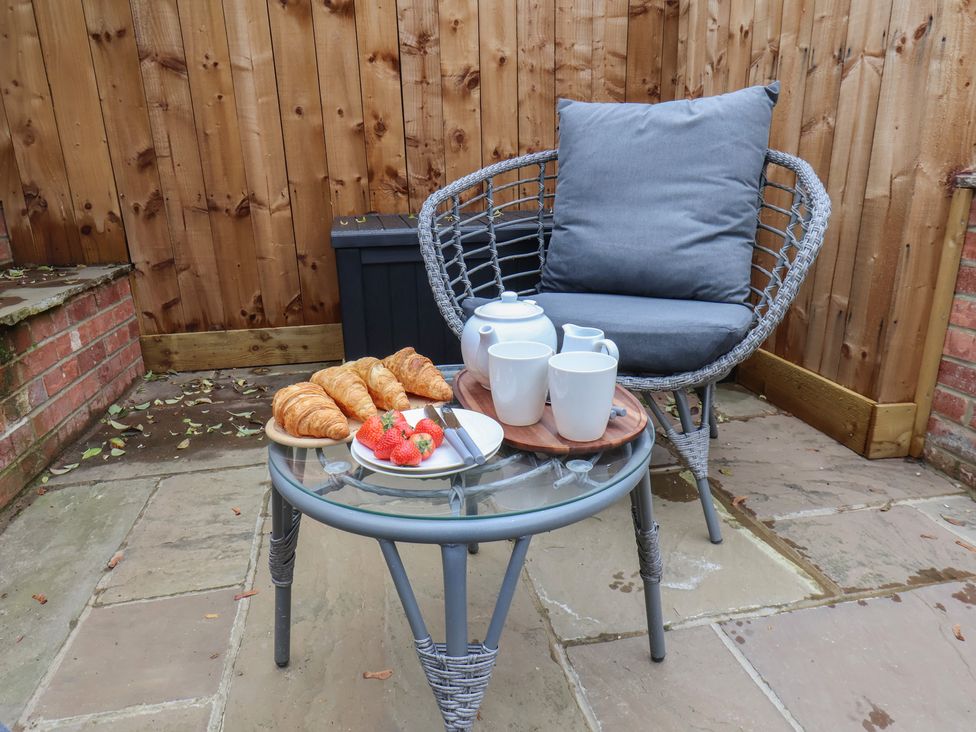 An outdoor seating area with a chair and a table holding tea and pastries at Arthur's House Middlesbrough