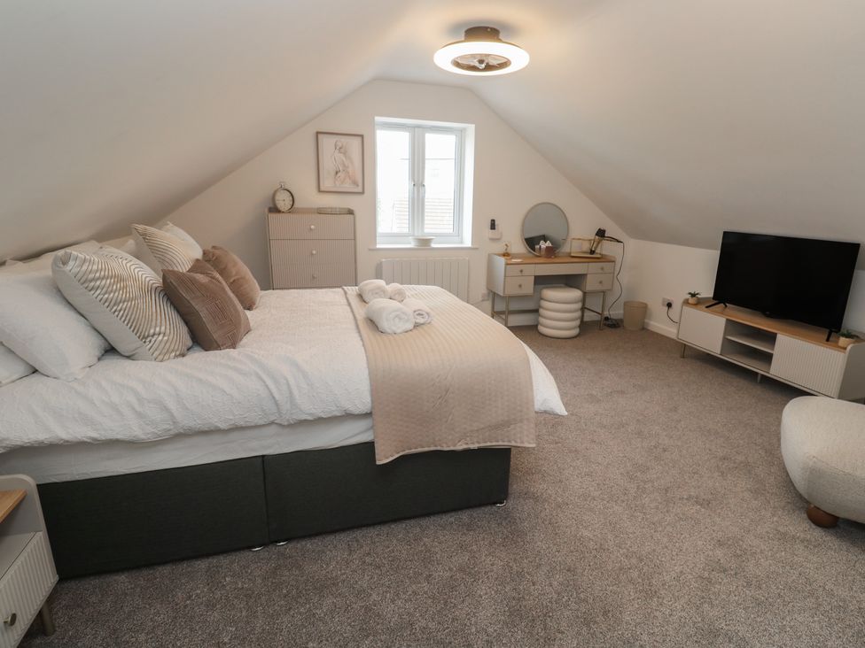 A bedroom with a bed, nightstand, dresser and television at Cosy Retreat