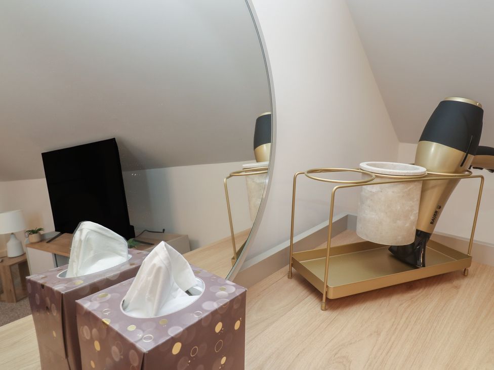 A table with a tissue box and hair dryer with a mirror at Cosy Retreat