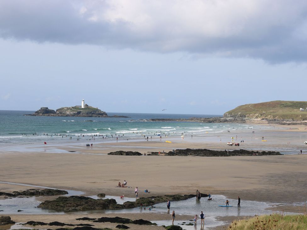 A beach with people and a lighthouse in the distance at Cosy Retreat 