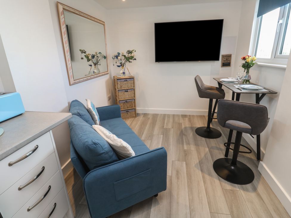 A living room with a sofa and television at Sea Whispers in Marazion
