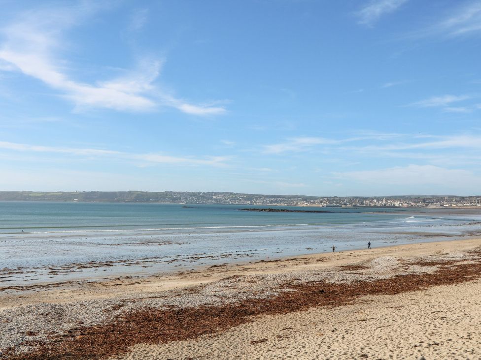 A beach with people walking along the shore at Sea Whispers in Marazion