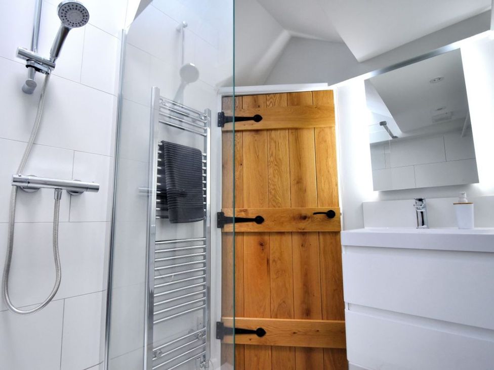 A bathroom with shower, towel radiator, mirror and wooden door at proposed 3 bed apartment Lyme Regis