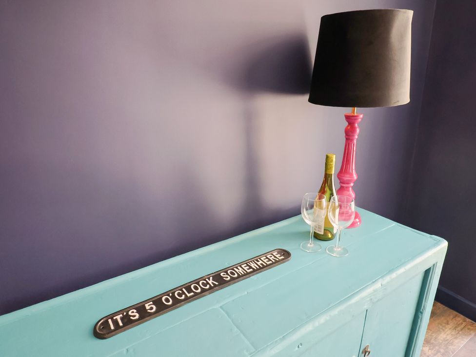 A table with a lamp, bottles, glasses, and a sign at Avocet in Lyme Regis