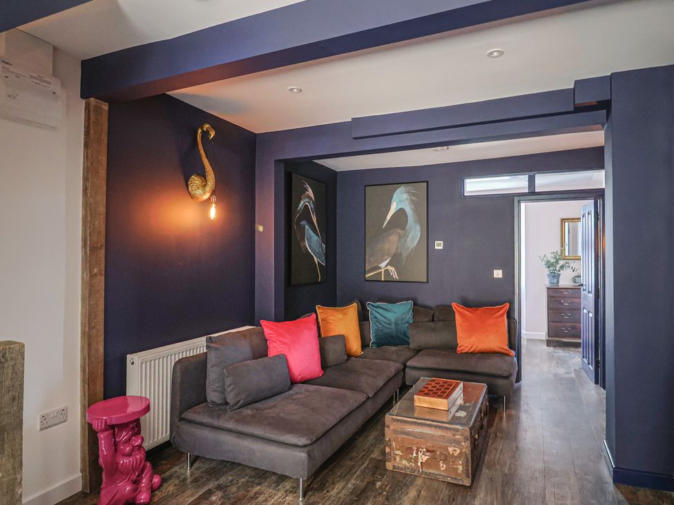 A living room with a sofa and wall art at Avocet in Lyme Regis