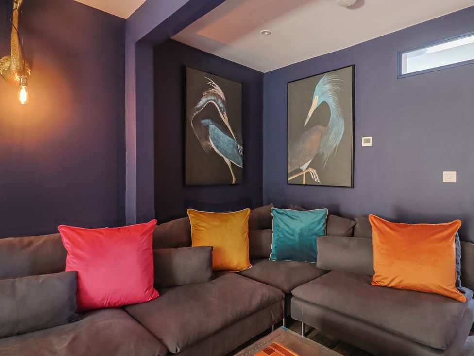 A living room with a sofa and wall art at Avocet in Lyme Regis