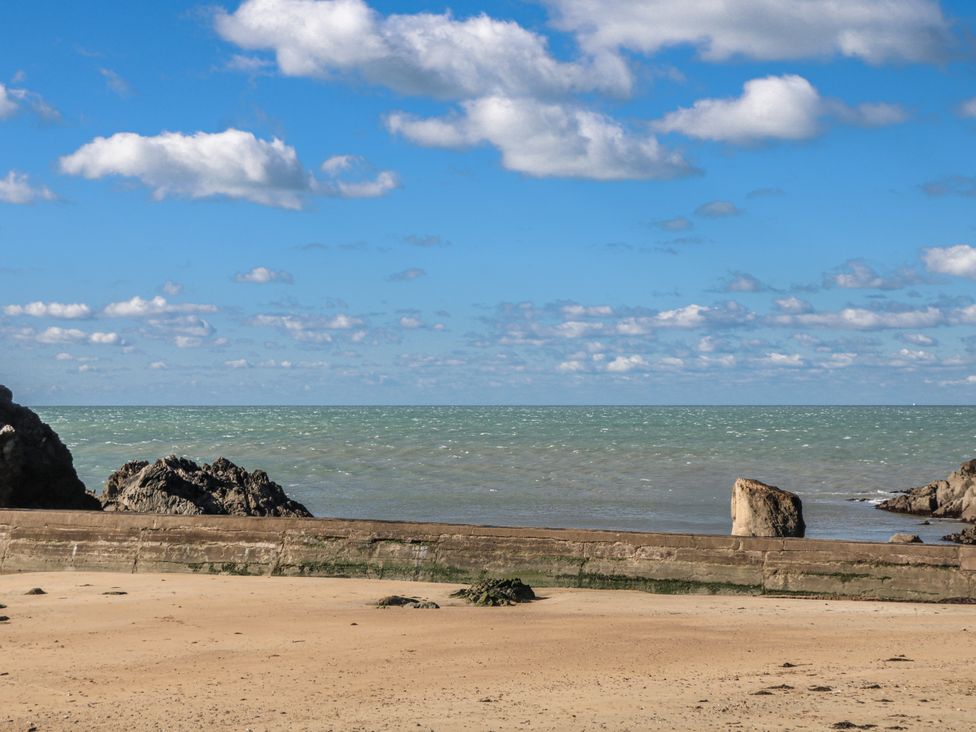 A beach with sand and rocks under a blue sky at 3 Brooks Cottages in Hope Cove