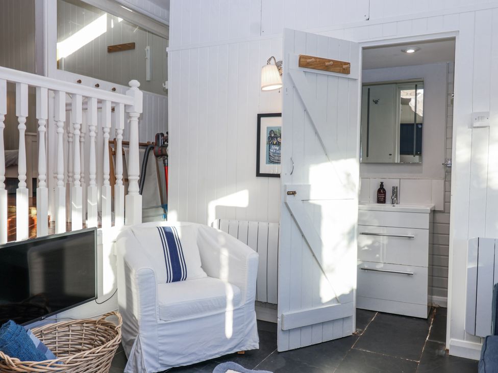 A living room with a chair and television at 3 Brook Cottages in Hope Cove