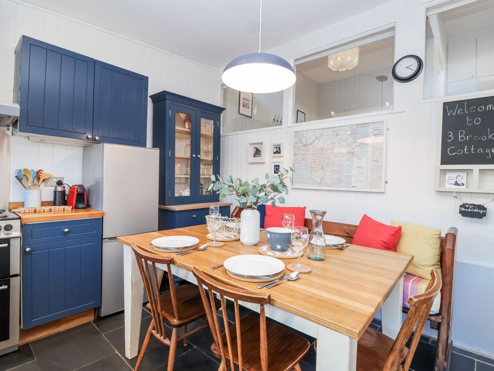 A kitchen with a dining table set and modern appliances at 3 Brook Cottages Hope Cove