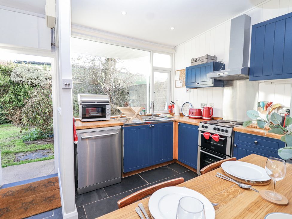 A kitchen with appliances and table at 3 Brook Cottages in Hope Cove