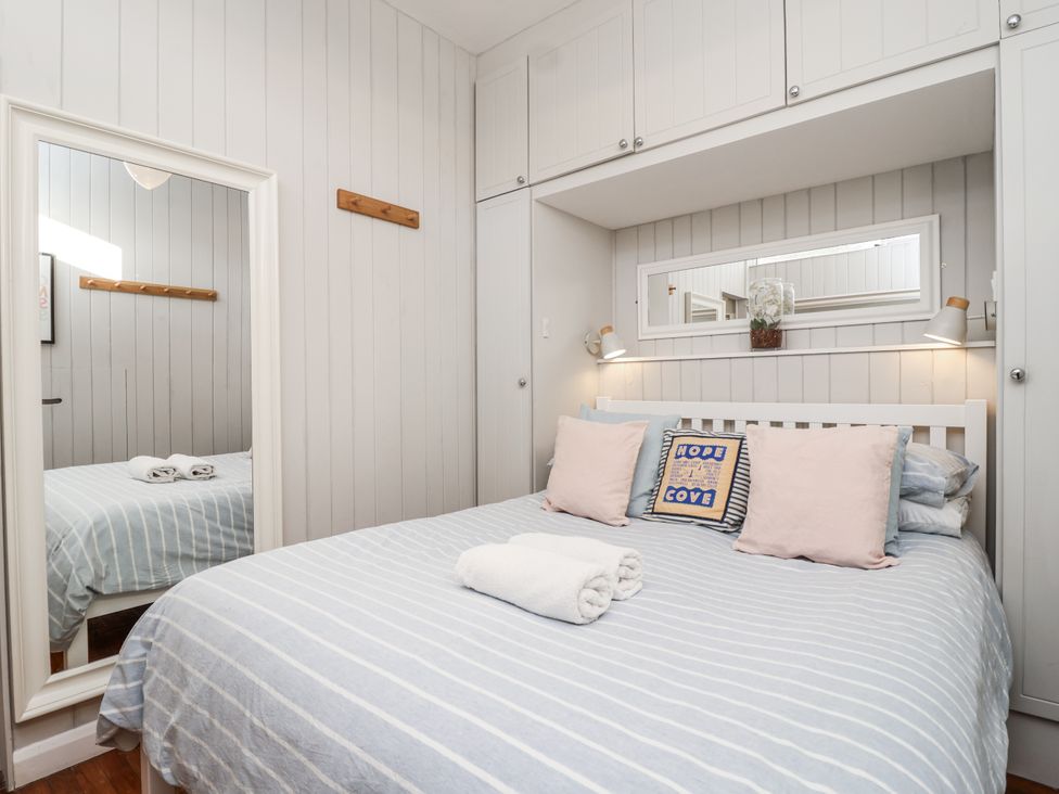 A bedroom with a bed and mirror at 3 Brook Cottages Hope Cove