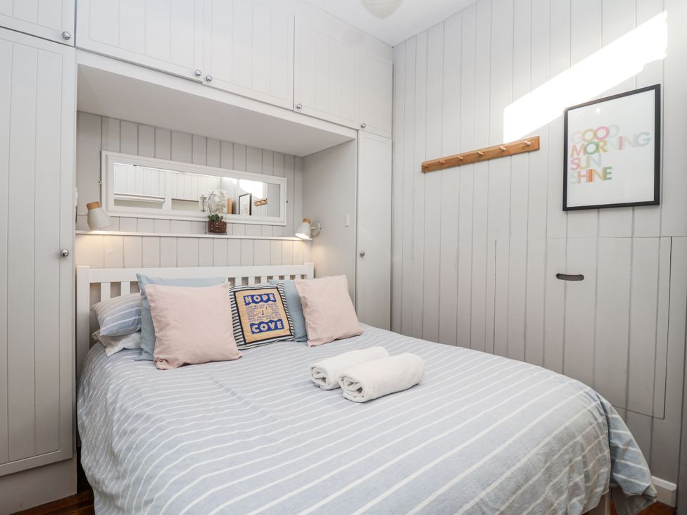 A bedroom with a bed and decorative items at 3 Brook Cottages in Hope Cove