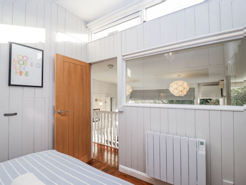 A bedroom with a door and a window at 3 Brook Cottages in Hope Cove
