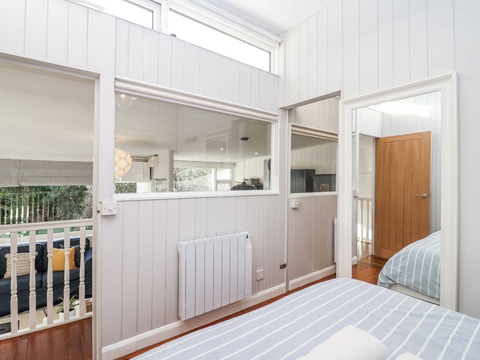 A bedroom featuring a bed, window, and door at 3 Brook Cottages in Hope Cove
