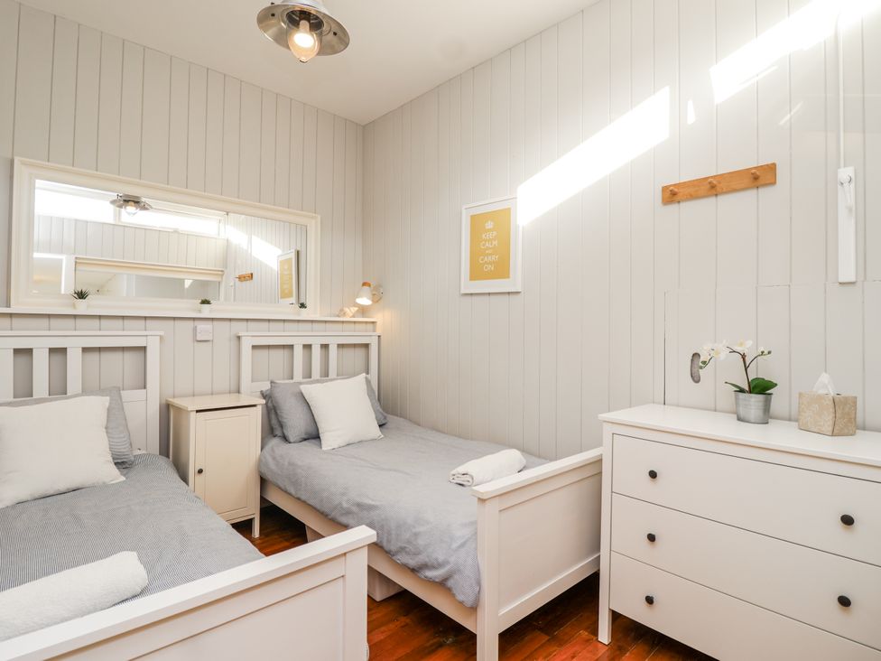 A bedroom with two beds and a mirror at 3 Brook Cottages in Hope Cove