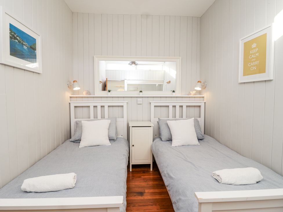 A bedroom with two single beds and a mirror at 3 Brook Cottages in Hope Cove