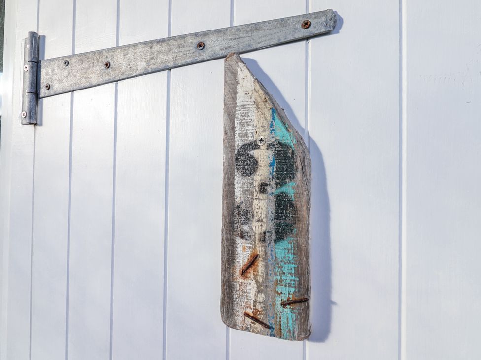 A wooden piece with a metal hinge attached on a white wall at 3 Brook Cottages in Hope Cove