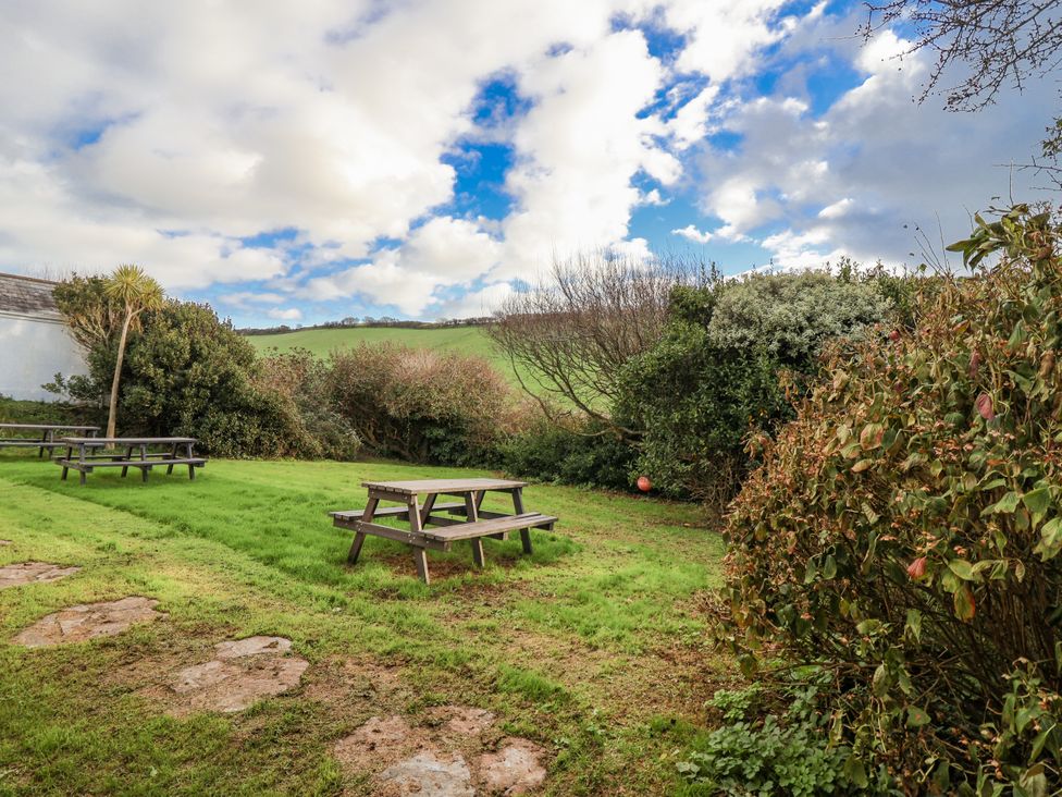 A garden with picnic tables and greenery at 3 Brook Cottages in Hope Cove