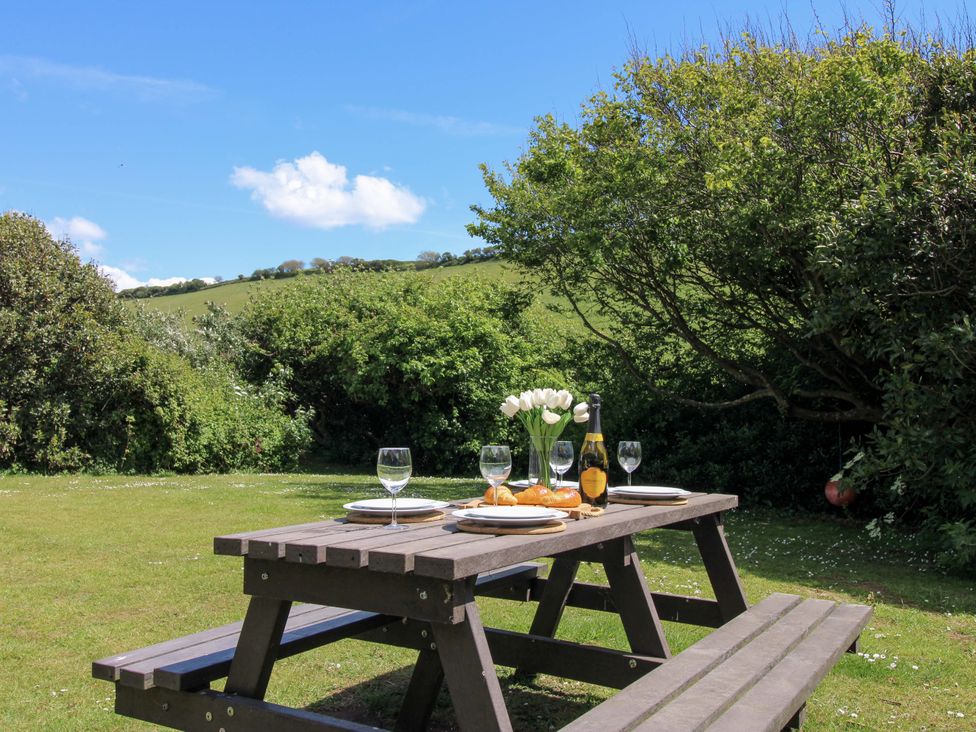 A garden with a picnic table and glasses at 3 Brook Cottages in Hope Cove